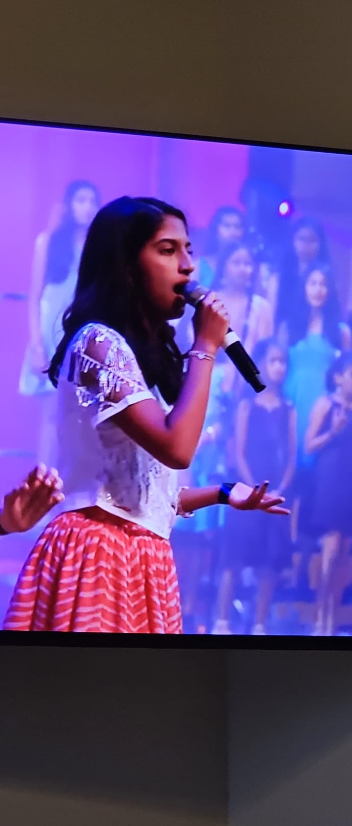 Vaishnavi singing on stage with microphone